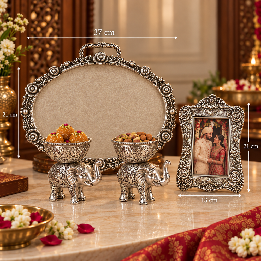 Ornate silver-toned decorative set on a marble table, including an oval tray, two elephant-shaped bowls holding sweets, and a framed picture. White dimension lines and labels show measurements: 37 cm width, 21 cm height, and 13 cm frame width.