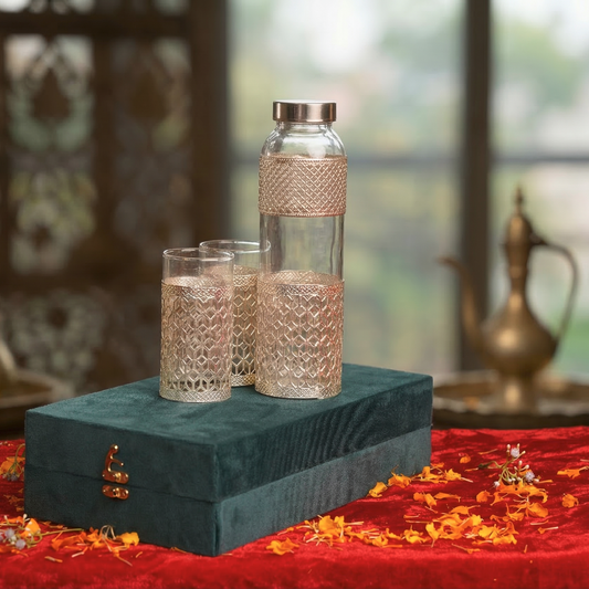 Decorative water bottle and glasses on a green box with a red fabric background