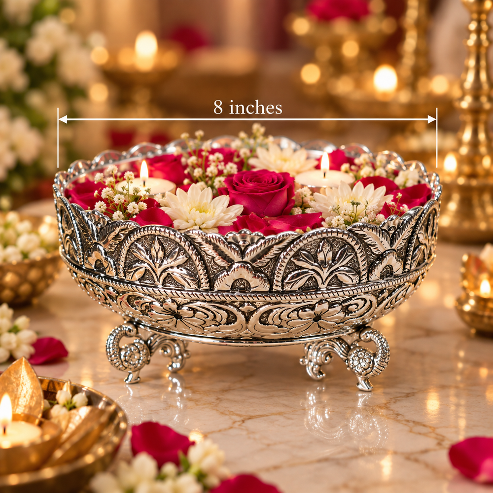 An ornate silver-toned decorative bowl with carved floral detailing and three legs, filled with red and white flowers and candles, shown on a marble surface with a warm blurred background. White text reads '8 inches' with a measurement arrow across the top.