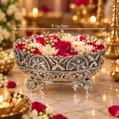 An ornate silver-toned decorative bowl with carved floral detailing and three legs, filled with red and white flowers and candles, shown on a marble surface with a warm blurred background. White text reads '8 inches' with a measurement arrow across the top.