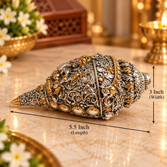 An ornate silver-toned shell-shaped decorative object with intricate gold and white detailing, shown on a marble surface with dimension lines indicating 5.5 inch length and 3 inch width.