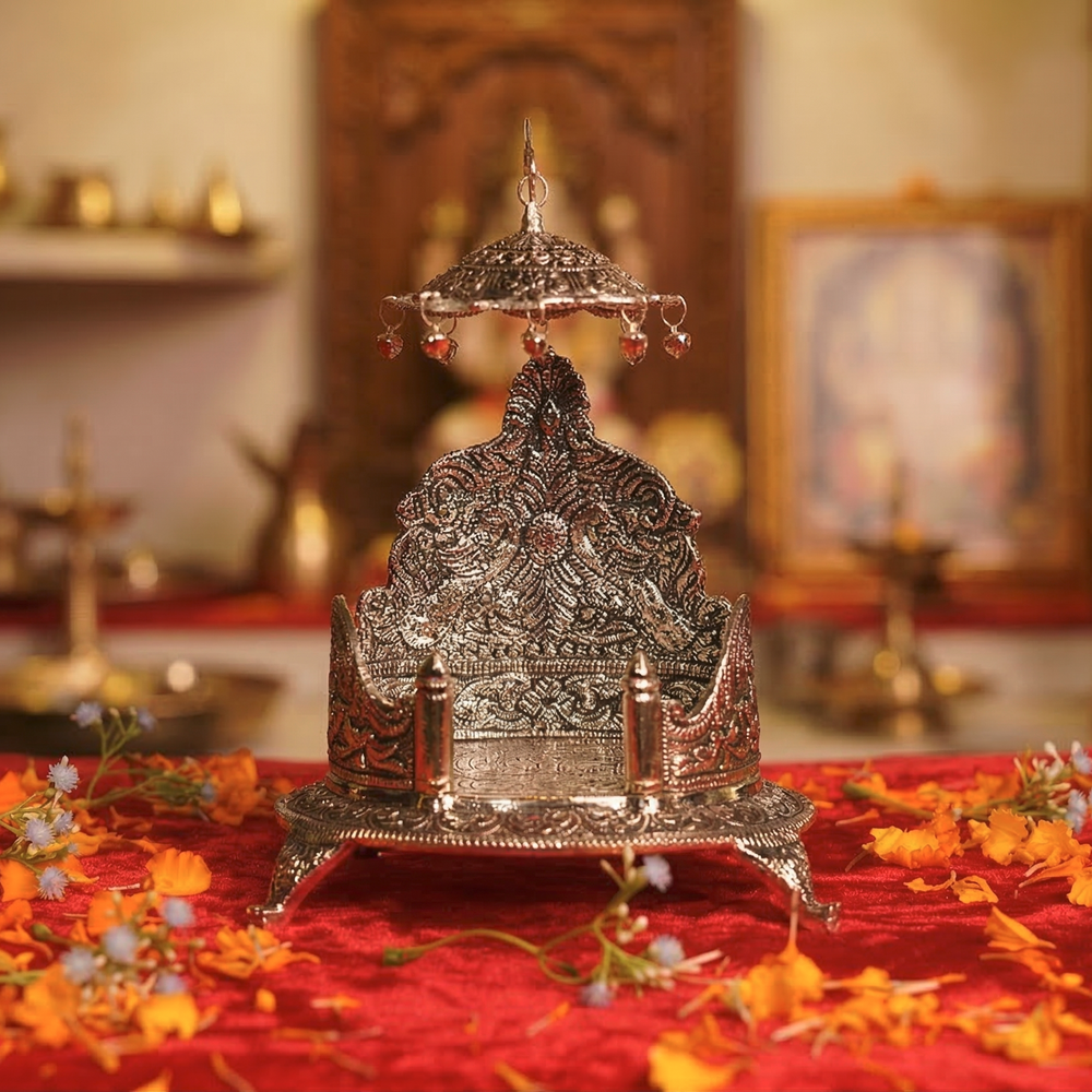 Decorative silver metal object on a red cloth with flowers, in a warm-toned room.