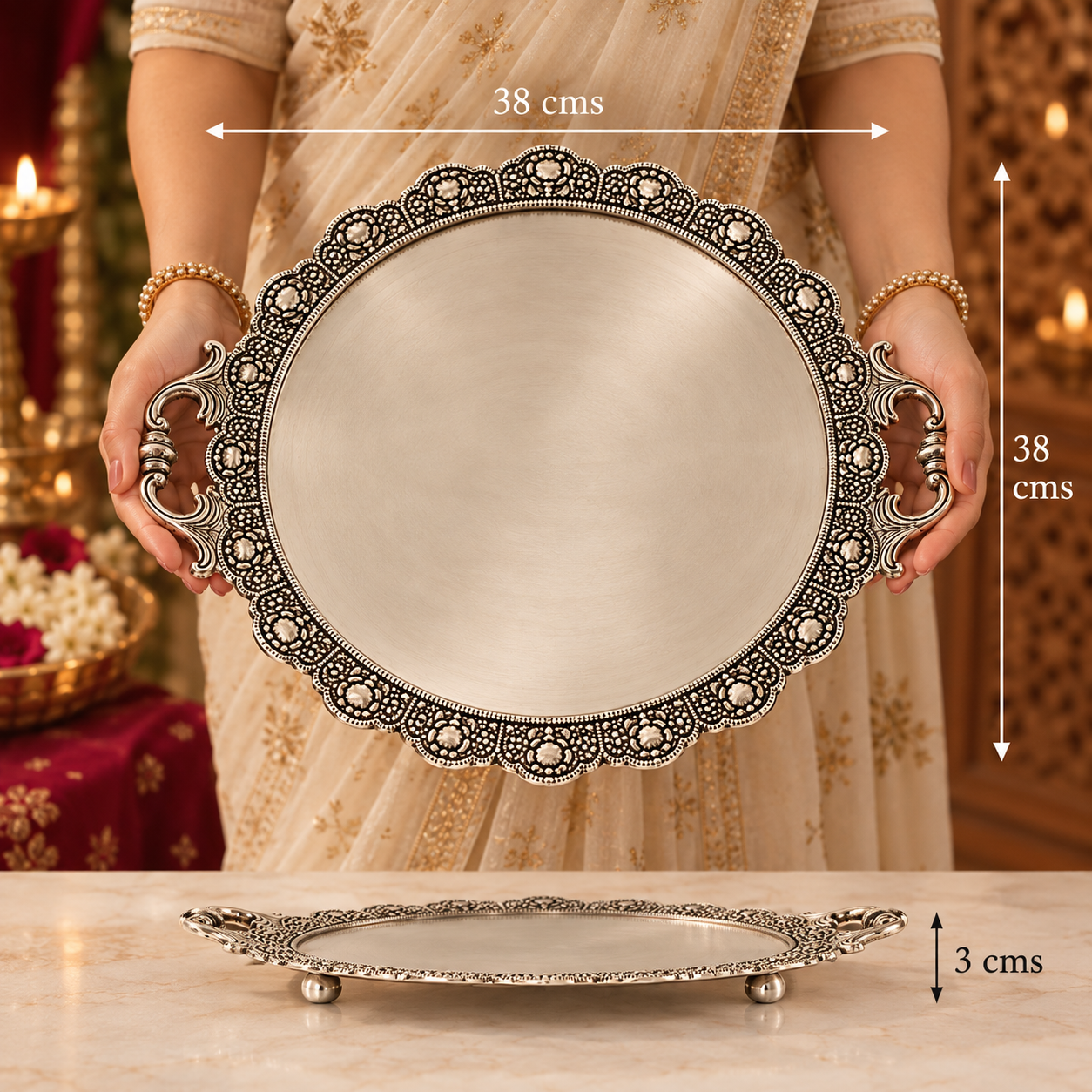 A person in a beige embroidered dress holds an oval silver-toned decorative tray with ornate filigree edges and side handles. The image includes dimension annotations showing the tray is 38 cm by 38 cm, with a smaller view of the tray on a marble surface below.
