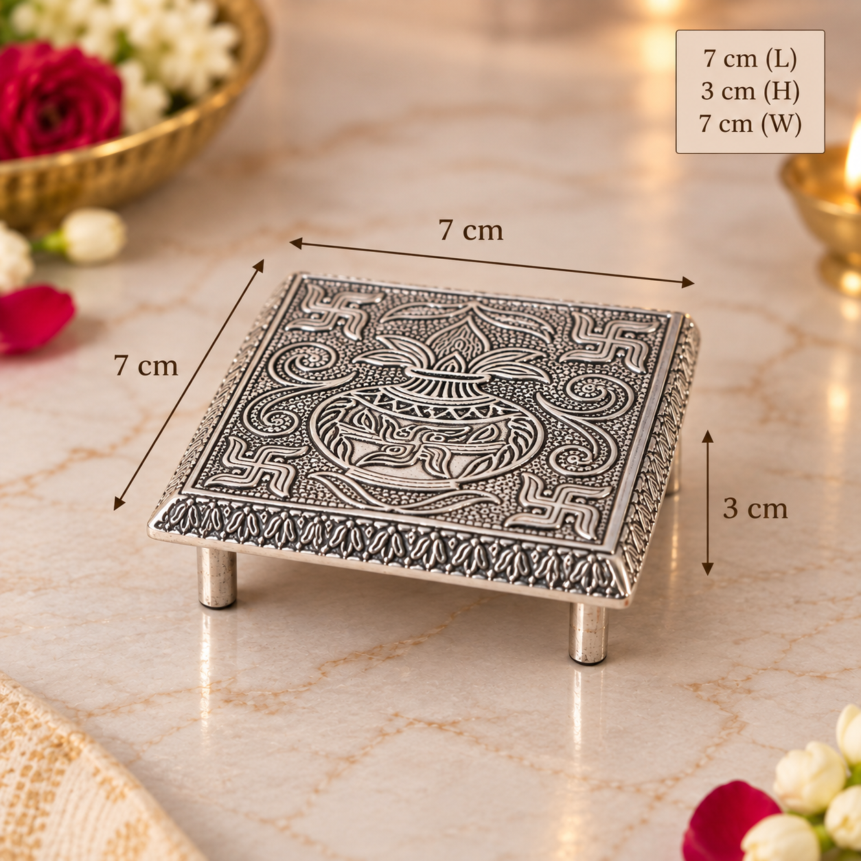 An ornate silver-toned metal stand with a carved deity Ganesha design, shown on a marble surface with dimension overlays indicating 7 cm length, 3 cm height, and 7 cm width.