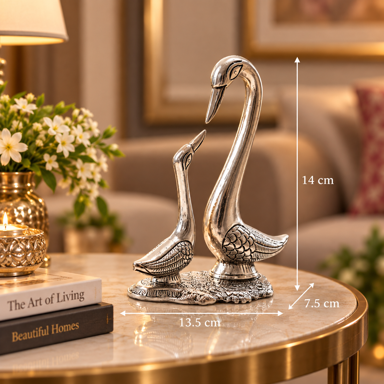 Silver-toned swan figurine set on a round table in a living room setting, with overlaid dimension lines showing 14 cm height, 13.5 cm width, and 7.