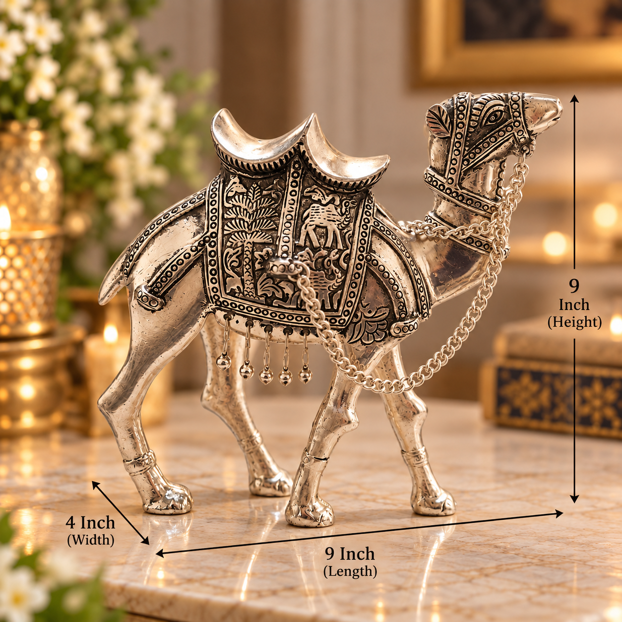 An ornate silver camel figurine with intricate embossed detailing and hanging bells, shown on a marble surface with overlaid dimension arrows and labels indicating 9 inch height, 9 inch length, and 4 inch width.