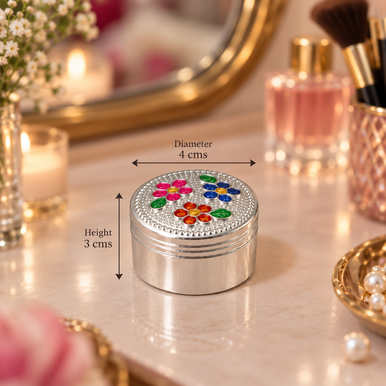 A small round silver metal cosmetic case with a lid decorated with colorful floral designs and rhinestones, shown on a vanity surface with size arrows indicating diameter 4 cm and height 3 cm.