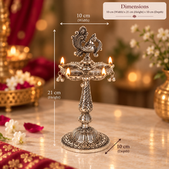 An ornate silver-toned multi-lamp oil lamp holder with lit candles, shown with overlaid dimension labels indicating 10 cm width, 21 cm height, and 10 cm depth on a warm decorative tabletop setting.