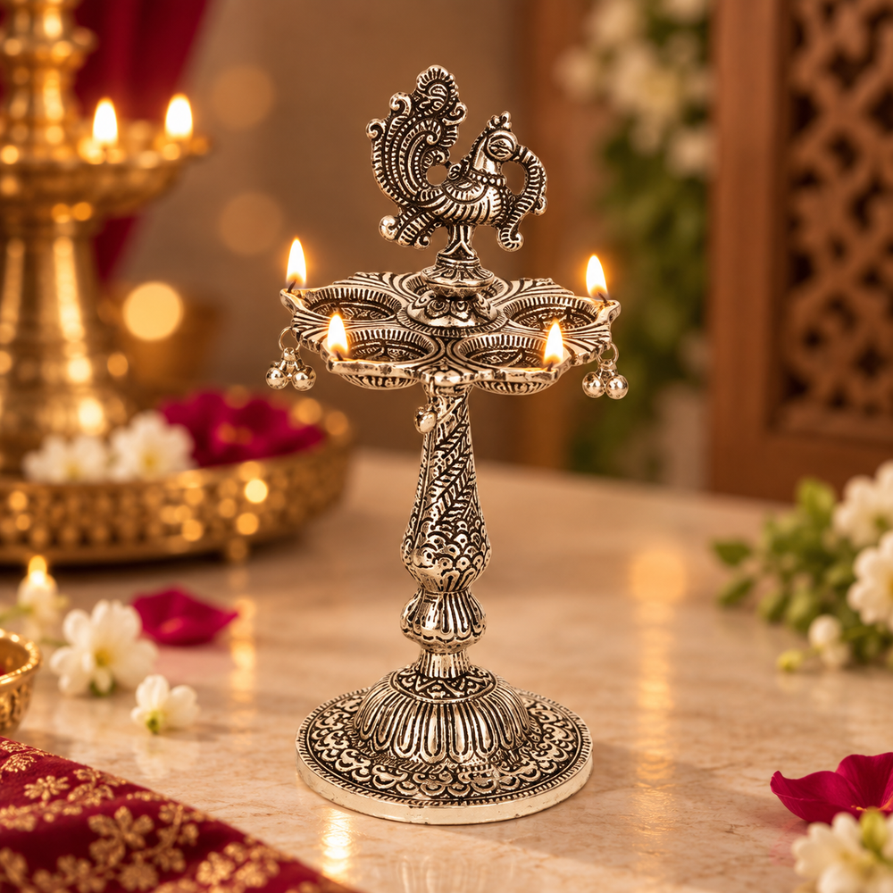 An ornate silver-toned brass oil lamp holder with multiple lit candles, set on a marble table in a decorated indoor setting with warm bokeh lights and floral accents.
