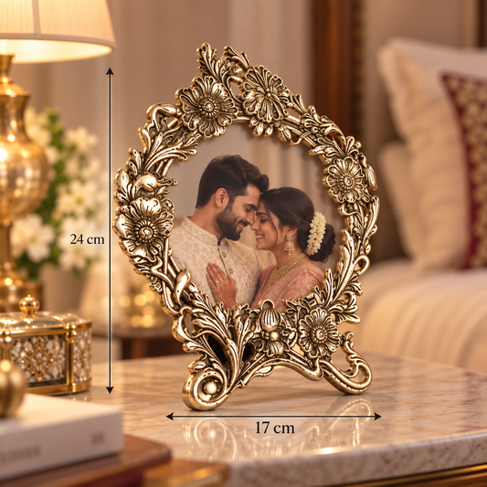 An ornate gold-toned round picture frame with floral scrollwork, shown standing on a marble table in a furnished room. A couple is visible inside the frame, and overlaid dimension lines indicate 24 cm height and 17 cm width.