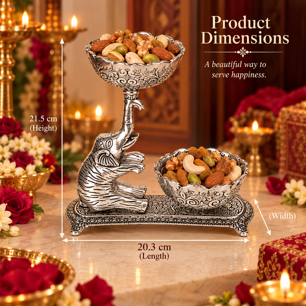 Silver-toned elephant-shaped serving tray filled with nuts and fruits, shown on a decorated table with candles and flowers. White dimension lines and text indicate product measurements: 21.