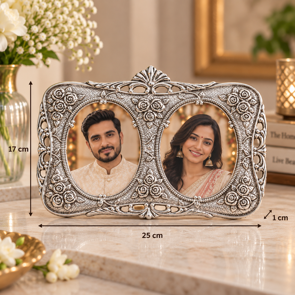 An ornate silver double-photo frame with detailed floral carvings, shown on a marble countertop with dimension lines indicating 25 cm width, 17 cm height, and 1 cm depth. The photos inside the frame show a man and a woman.