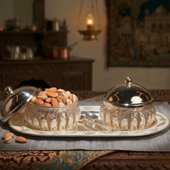 Decorative glass containers with almonds on a tray in a warm, dimly lit room.