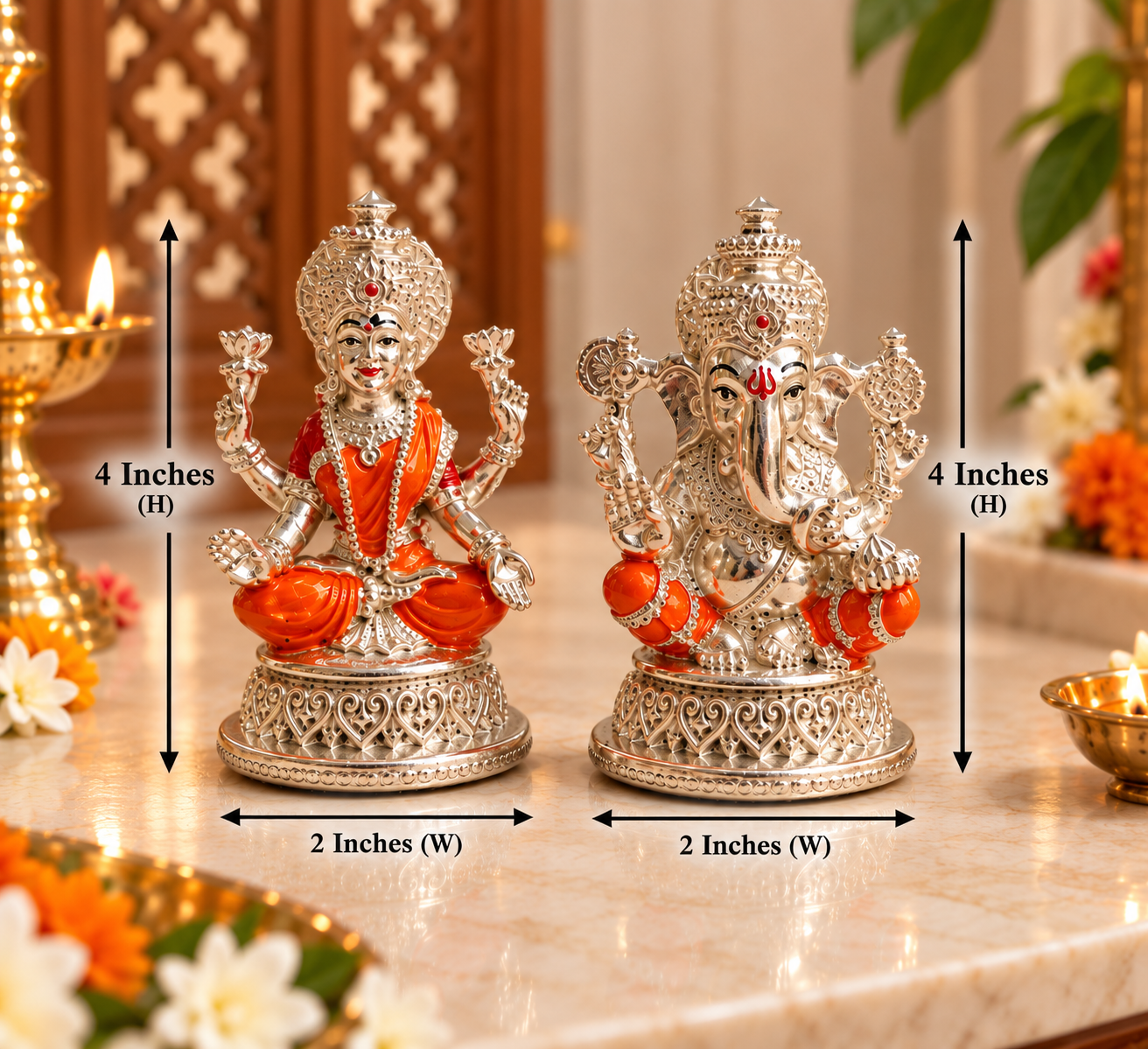 Two ornate silver deity figurines on a marble surface with overlaid dimension arrows and text showing 4 inches height and 2 inches width. The left figurine is seated in orange robes, and the right figurine is more detailed in silver with small orange accents.
