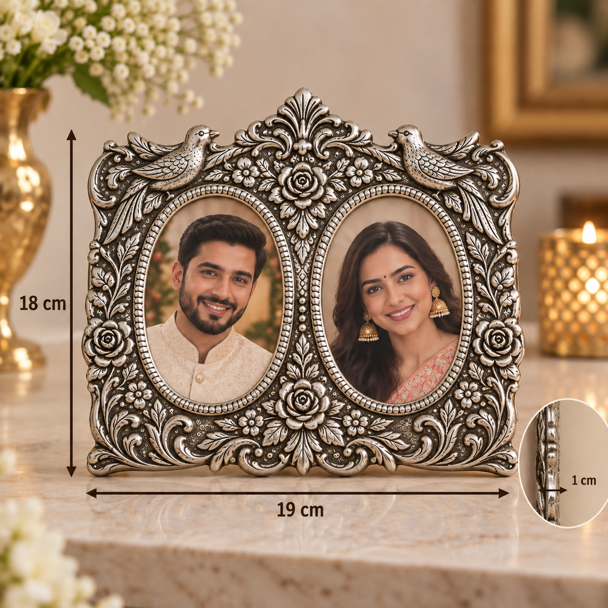 An ornate silver-toned double oval photo frame with floral and bird details, shown on a marble surface with overlaid dimension markers indicating 18 cm height, 19 cm width, and a 1 cm inset detail. Two sample portrait photos are inserted into the oval openings.
