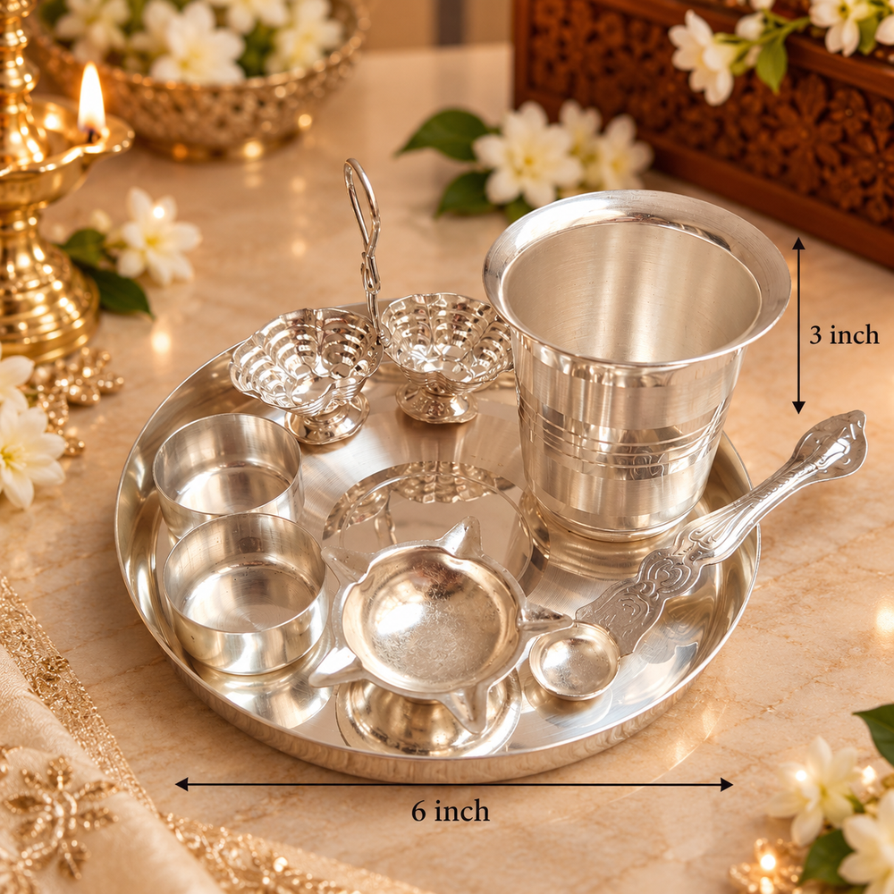 A silver stainless steel puja set arranged on a round tray, including a 3-inch cup, small bowls, a spoon, and decorative pieces, shown on a beige marble surface with dimension markers indicating 6 inch diameter and 3 inch height.