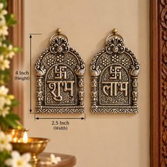 Two ornate metallic wall hanging plaques with engraved script and decorative motifs, shown side by side on a beige wall with dimension labels indicating 4 inch height and 2.5 inch width.