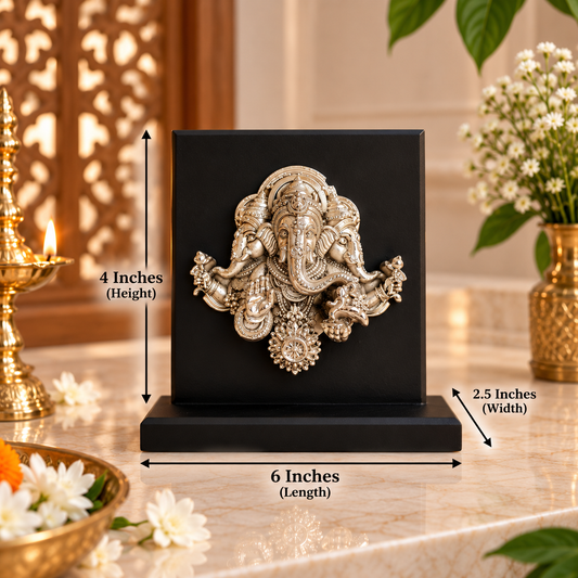 A black square decorative plaque featuring a raised metallic Ganesha motif, shown on a marble surface with dimension arrows and labels indicating 6 inches length, 4 inches height, and 2.5 inches width.