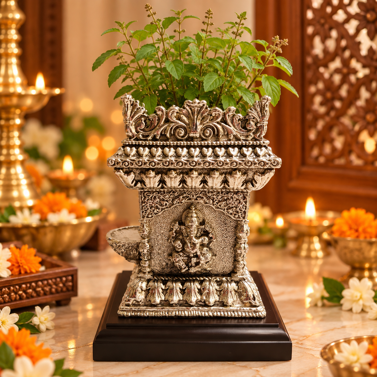 An ornate silver-toned decorative planter shaped like a miniature temple, filled with green leafy stems, displayed on a dark wooden base on a marble surface with warm ambient lights and floral decor in the background.