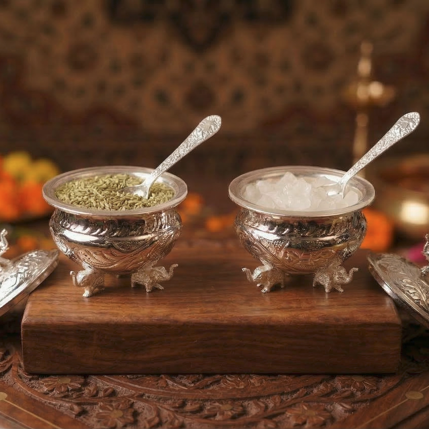 Two silver bowls with spoons on a wooden surface with a blurred background